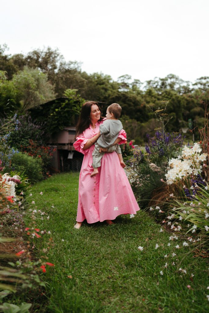 woman in pink dress twirling in a flower garden showing you can wear colour in your family photos 