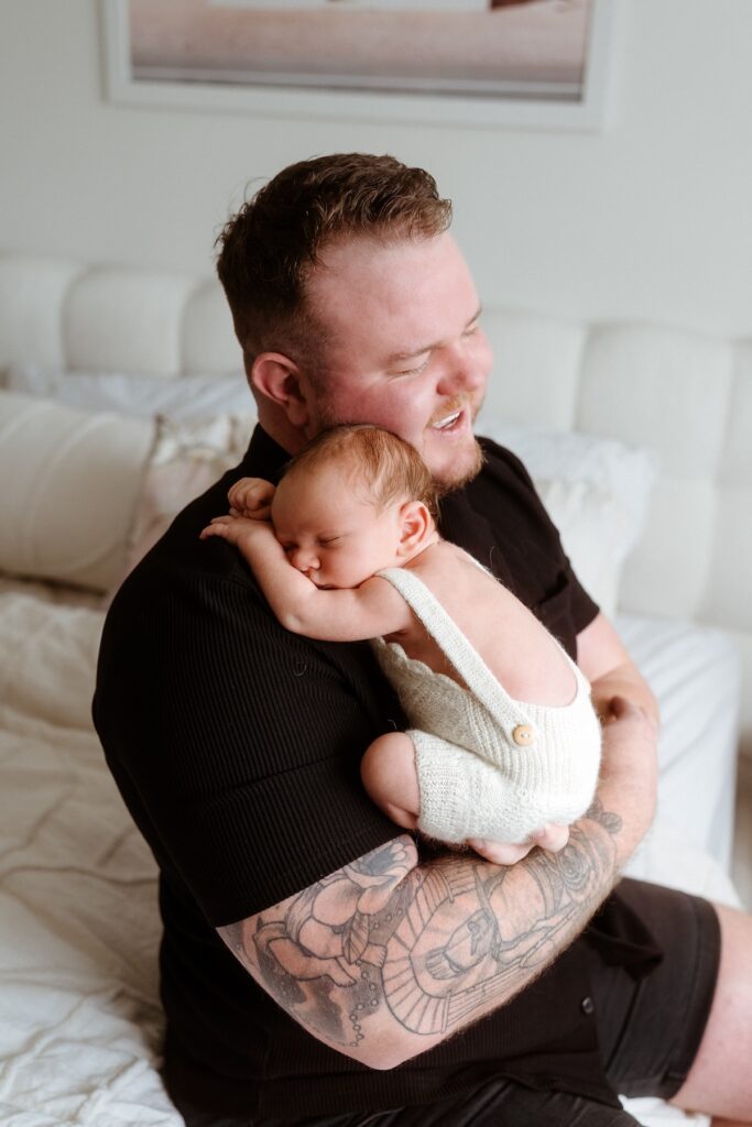 man holding newborn baby on his chest showing you can wear black to your family photos