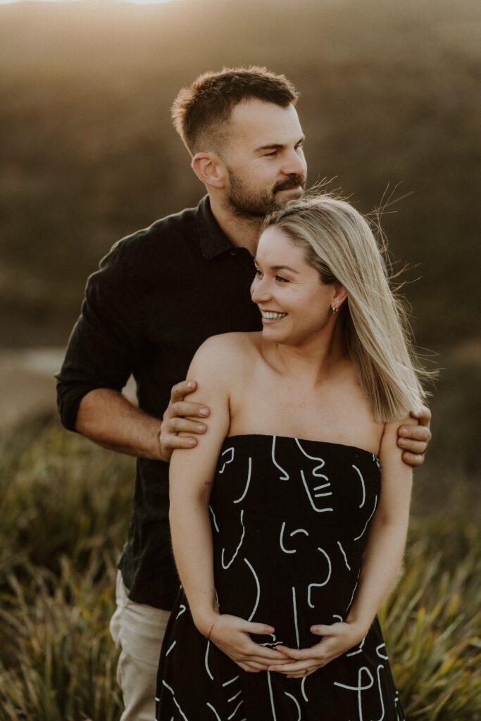 man holding pregnant shoulders from behind showing you can wear black to your family photos