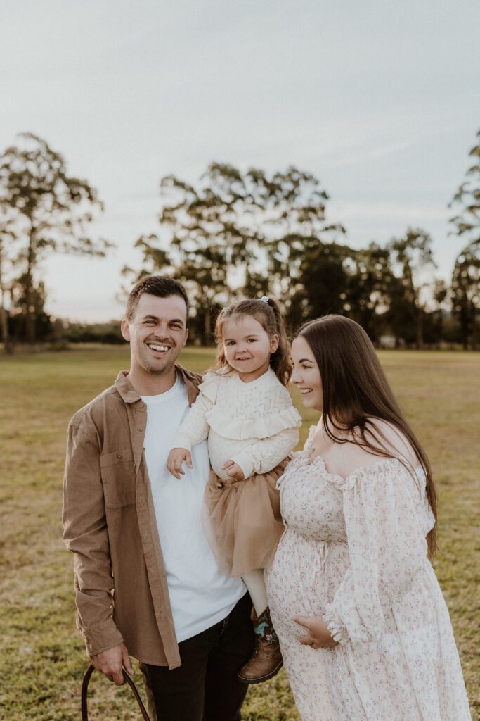 man holding small child and smiling at pregnant wife in maternity photos what to wear
